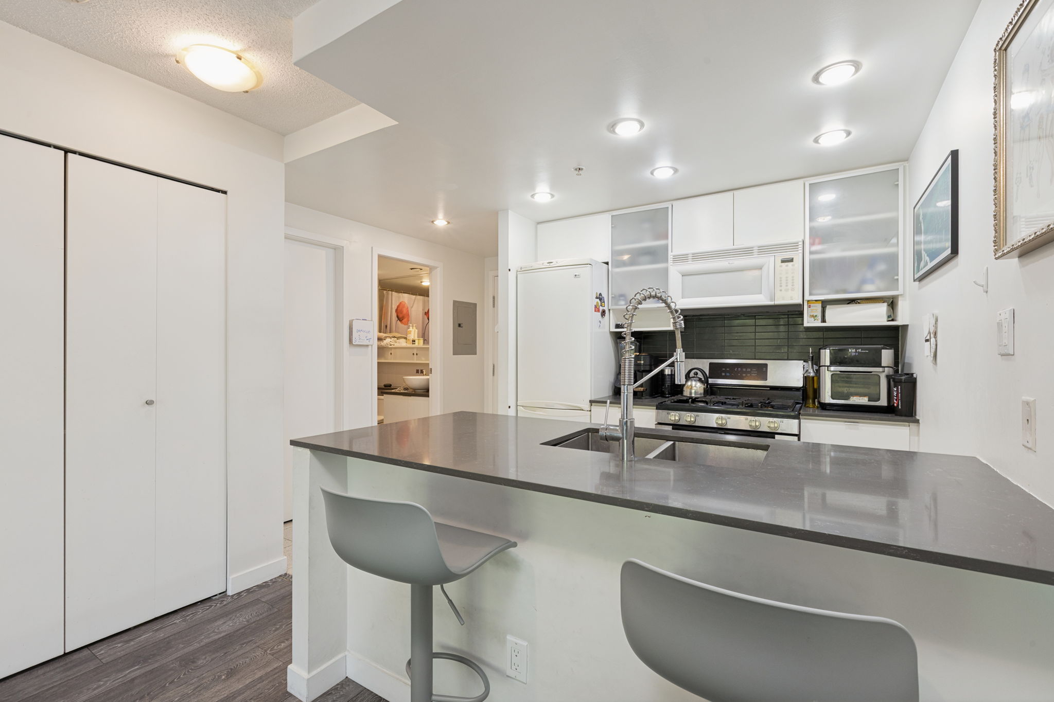 The kitchen along its full length, with the bathroom doorway off the entry hall.
