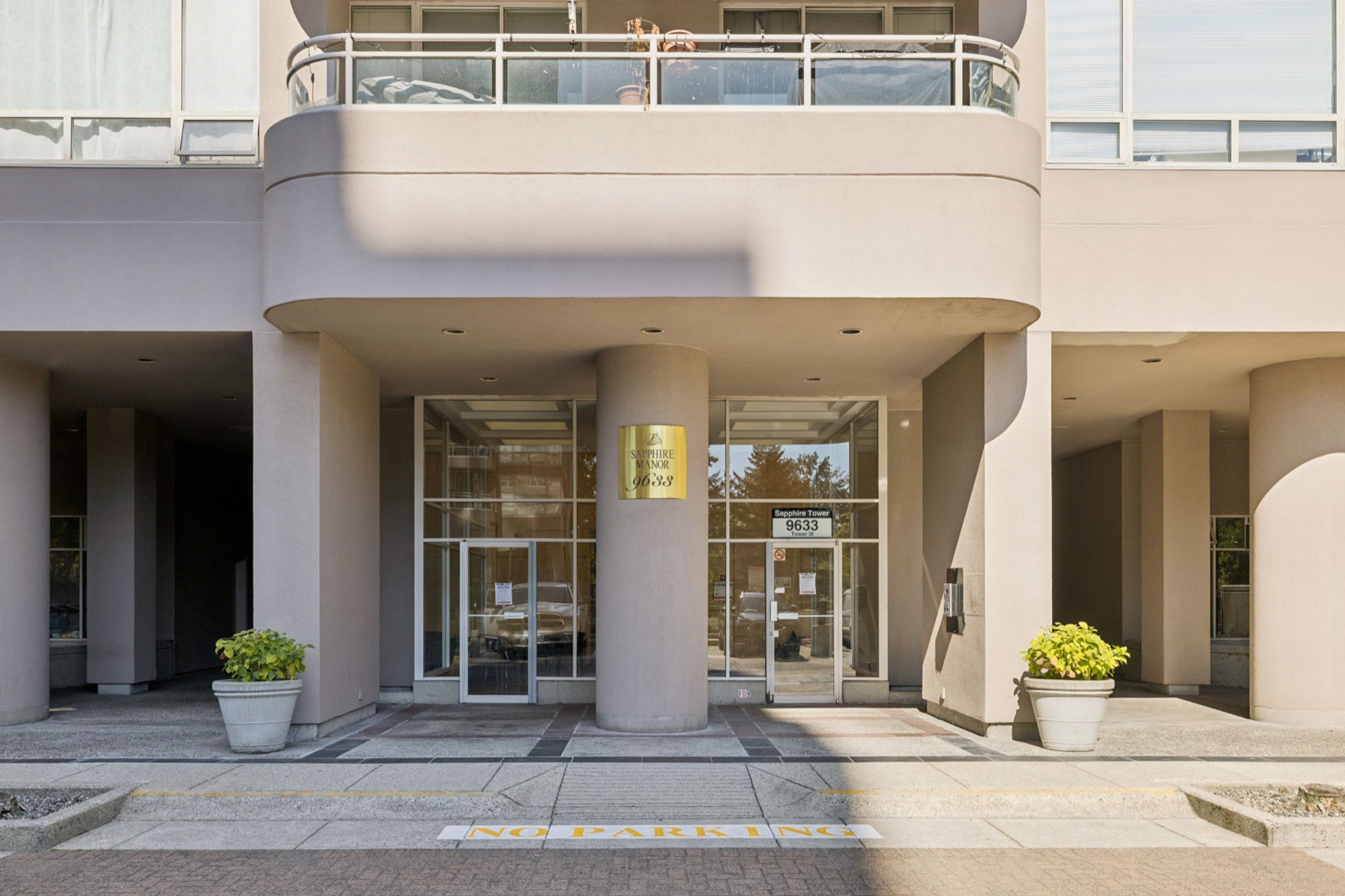 The entrance, glass doors under the curved balconies with planters either side.