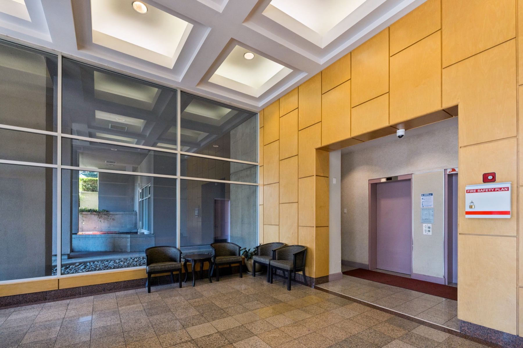 The lobby, seating beside the glass and the lift doors beyond.