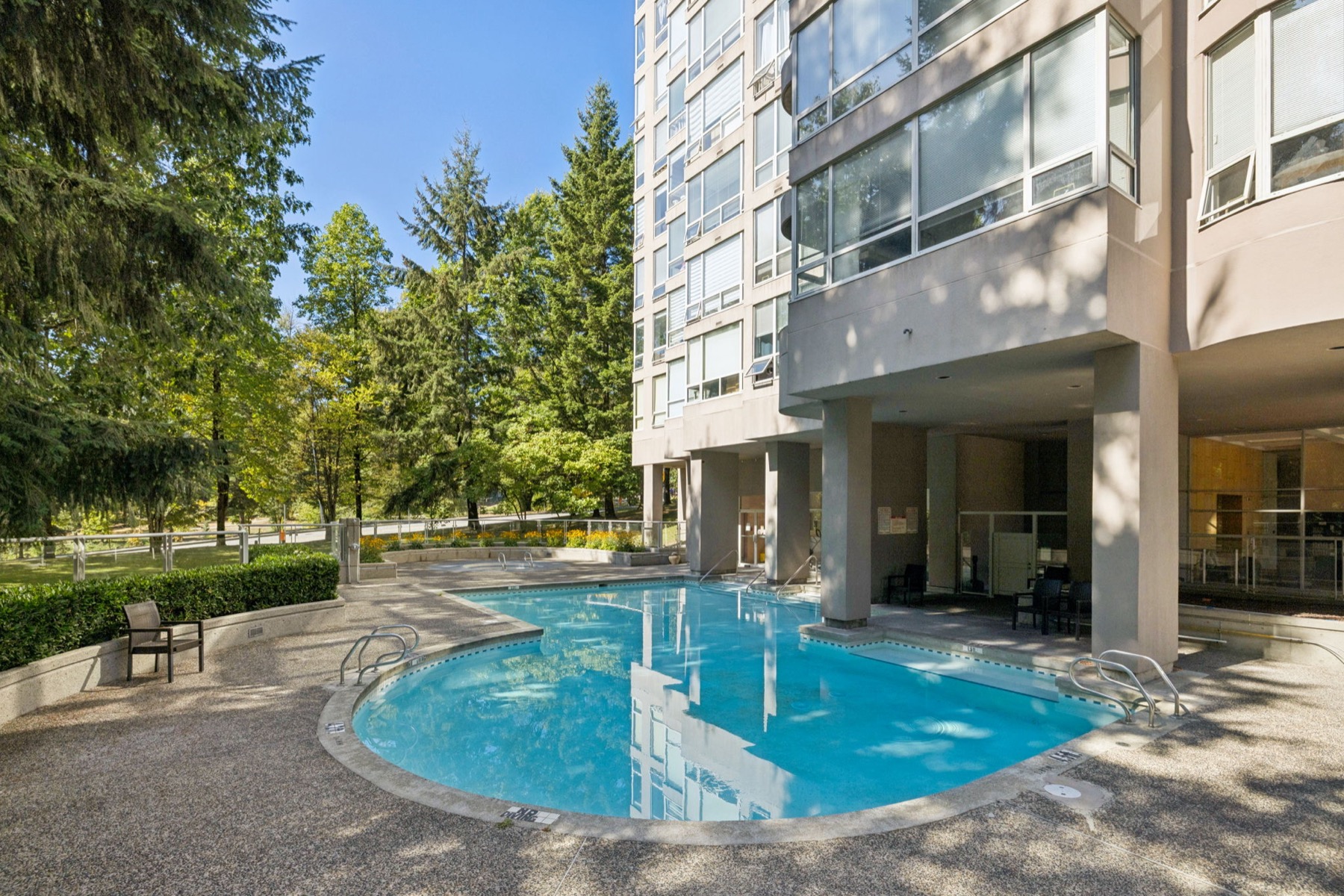 The outdoor pool at the foot of the tower, trees around it.