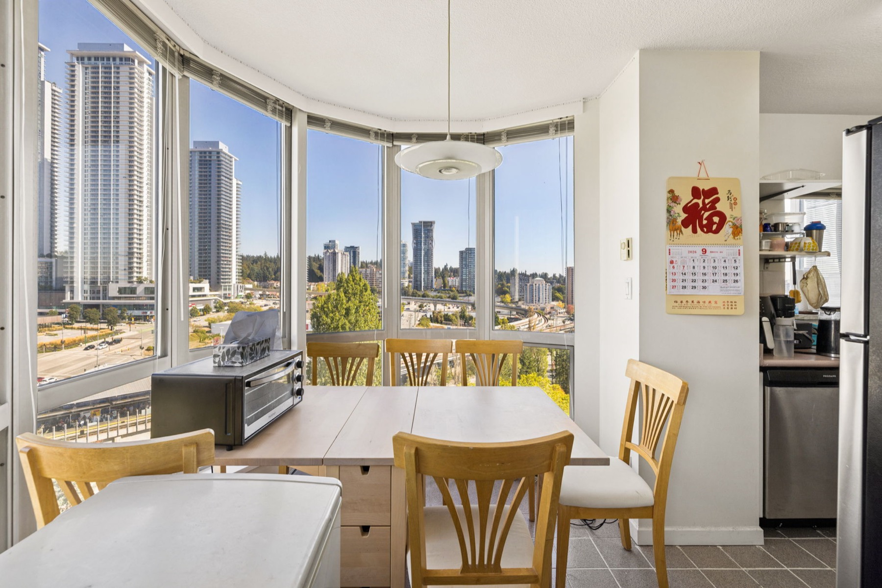 The dining area in the curved bay window, a table set within the glass and the towers of Lougheed behind it.