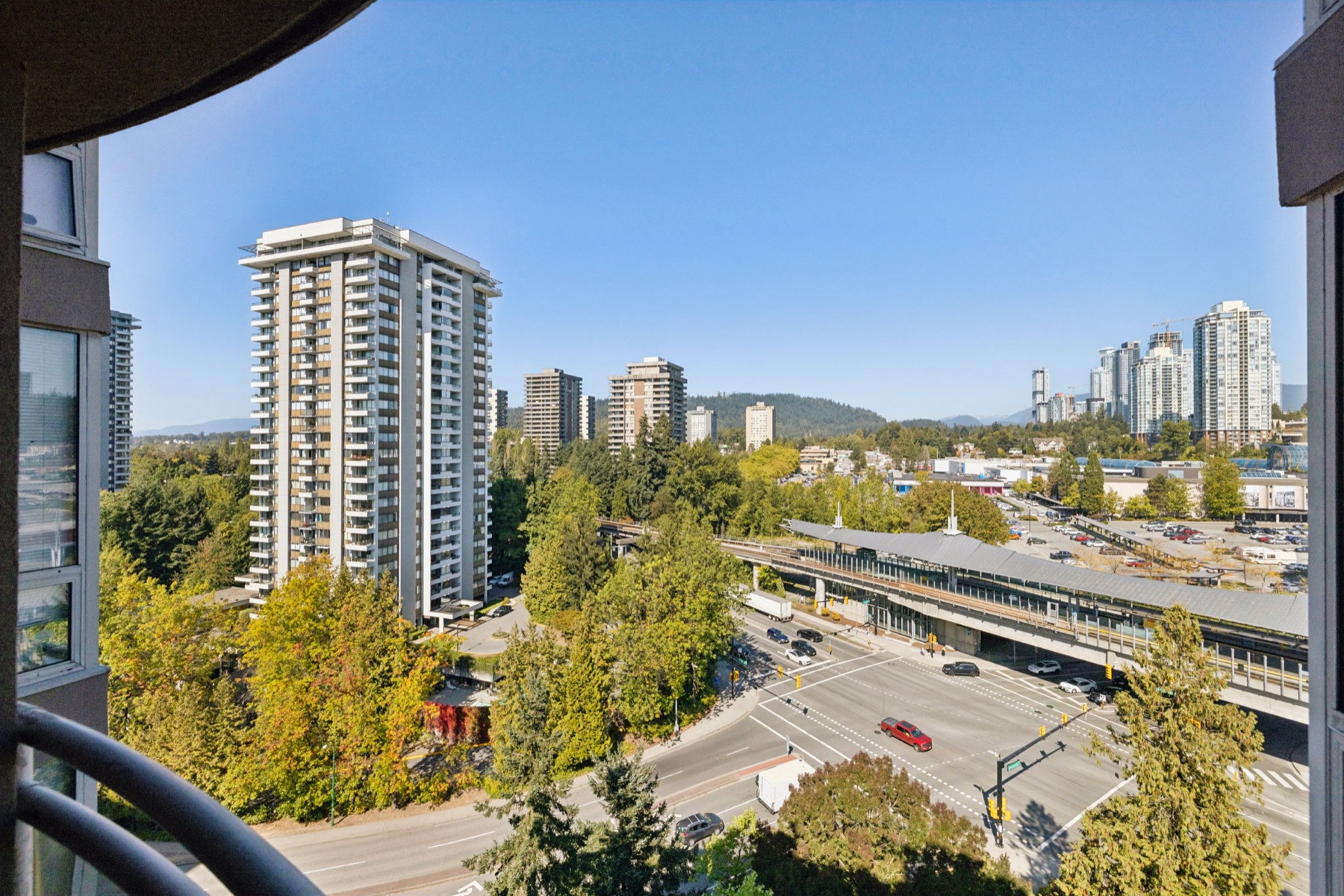 Down from the balcony to the SkyTrain line and the towers beyond the trees.